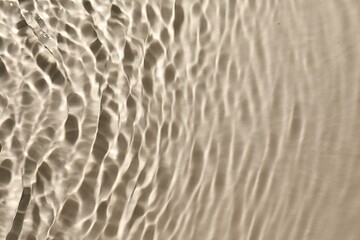 Rippled surface of clear water on beige background, top view
