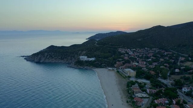 Drone aerial view of Solanas beach with turquoise water and mountain landscape at sunset in Sardinia, Italy