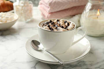 Cup of aromatic hot chocolate with marshmallows served on white marble table, closeup