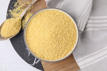 Bowl and spoon with raw couscous on table, flat lay