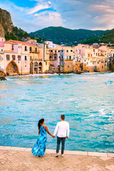 couple of men and woman on vacation in Sicily visiting the old town of Cefalu, sunset at the beach...