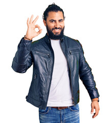 Young arab man wearing casual leather jacket smiling positive doing ok sign with hand and fingers. successful expression.