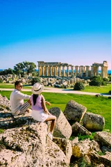 Deurstickers A couple of men and woman visit the Greek temples at Selinunte Sicily during vacation, View on the ocean sea and ruins of Greek columns in Selinunte Archaeological Park Sicily Italy © Fokke Baarssen