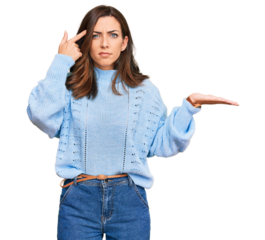 Young brunette woman wearing casual winter sweater confused and annoyed with open palm showing copy space and pointing finger to forehead. think about it.