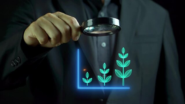 Business man handle a magnifying glass that showing growth digital tree graph illustration with arrow up icon. The concept for green earth, environment, or growth and success.