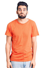 Young handsome man with beard wearing casual t-shirt puffing cheeks with funny face. mouth inflated with air, crazy expression.