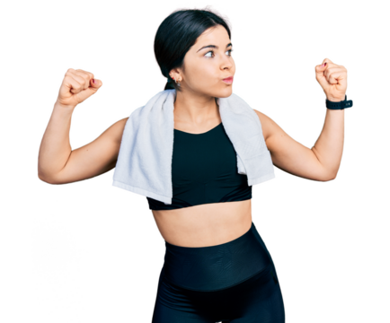 Young brunette woman with blue eyes wearing sportswear and towel showing arms muscles smiling proud. fitness concept.