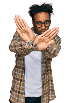 Young african american man with beard wearing casual clothes and glasses rejection expression crossing arms doing negative sign, angry face