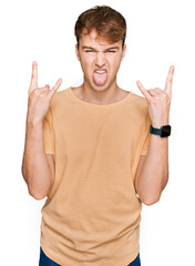 Young caucasian man wearing casual clothes shouting with crazy expression doing rock symbol with hands up. music star. heavy music concept.