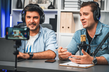 Host channel of creative broadcaster living by smartphone in positive podcast with special guest in list script to advice listeners, wearing headsets, using mic radio record at studio. Sellable. - obrazy, fototapety, plakaty