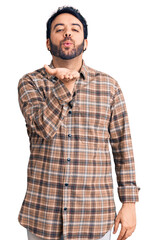 Young hispanic man wearing casual clothes looking at the camera blowing a kiss with hand on air being lovely and sexy. love expression.