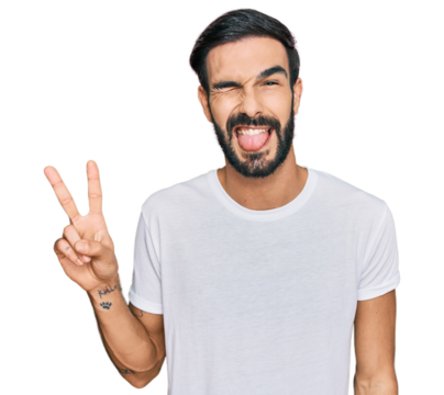 Young hispanic man wearing casual white t shirt smiling with happy face winking at the camera doing victory sign. number two.