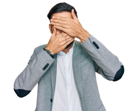 Young hispanic man wearing business clothes covering eyes and mouth with hands, surprised and shocked. hiding emotion