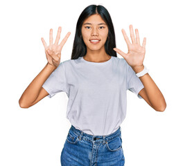 Beautiful young asian woman wearing casual white t shirt showing and pointing up with fingers...