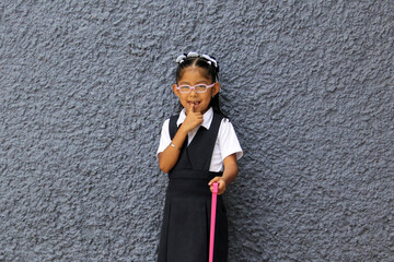 4 year old Latina brunette girl with public school uniform, eye glasses and backpack is ready to...