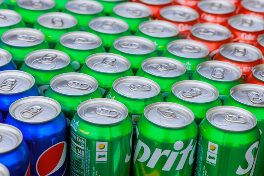 Many aluminum cans of sparkling drinks Sprite, Coca-Cola, Pepsi staying in rows.