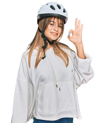 Teenager caucasian girl wearing bike helmet smiling positive doing ok sign with hand and fingers. successful expression.