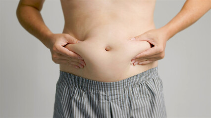 Naklejka premium close up of man hand pinching excessive belly fat