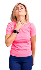 Young blonde woman wearing sportswear touching painful neck, sore throat for flu, clod and infection