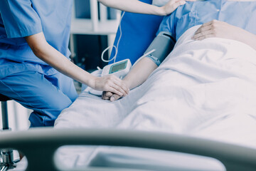 Side view of diverse doctors examining Asian female patient in bed in ward at hospital.