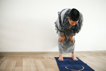 Senior Asian muslim man doing salat with ruku gesture on the praying mat