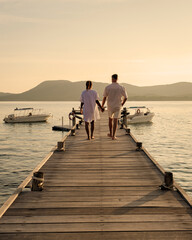 A couple at a wooden pier in the ocean during sunset in Samaesan Thailand - obrazy, fototapety, plakaty