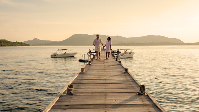 a couple walking at a wooden pier in the ocean during sunset in Samaesan Thailand - Powered by Adobe
