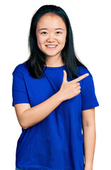 Young chinese woman wearing casual blue t shirt smiling cheerful pointing with hand and finger up to the side