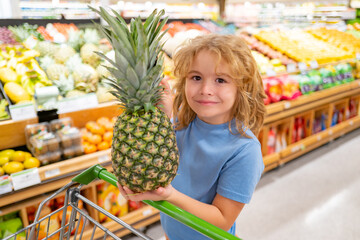 Kid on shopping. Child with shopping basket full of vegetables and fruits. Kid in a food store. Supermarket shopping and grocery shop concept. Child with shopping basket.
