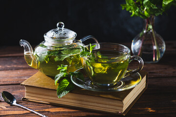Mint tea in a teapot and cup on a wooden table