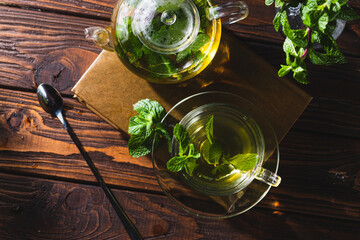 Mint tea in a teapot and cup on a wooden table
