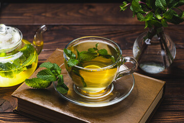 Mint tea in a teapot and cup on a wooden table