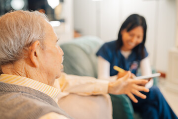Elder man talking to a nurse visiting him at home