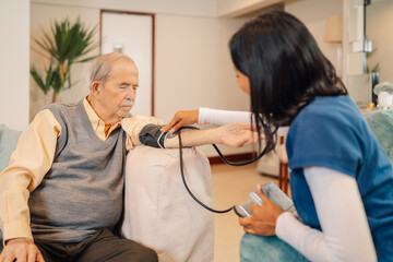 Home nurse measuring blood pressure of a old man