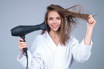 Young brunette woman with hair dryer on studio background. Hairs style and beauty concept....