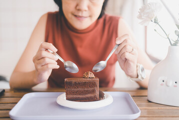 Happy women hands holding spoon and eating tasty chocolate cake in a cafe