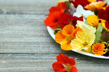 Low calories salad of lettuce and flowers on the wooden table.