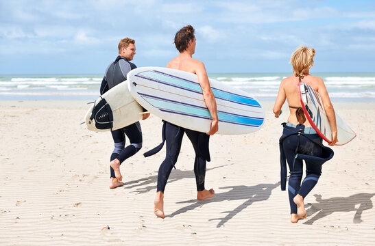Surfer friends, running and back at beach with board, training or fitness on vacation in summer. Men, woman and surfboard for wellness, health or workout by ocean, waves or freedom on holiday on sand