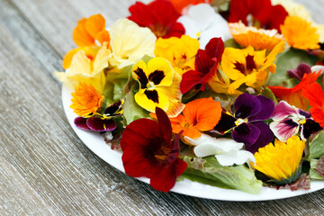 Low calories salad of lettuce and flowers on the wooden table.
