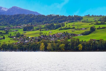 Grand mountain houses Swiss residences by Interlaken laker under cloudy-blue sky background 