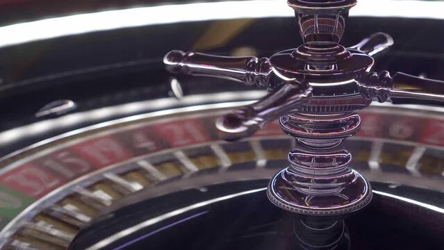 Close-up shot of a shiny silver European roulette wheel with red and black colors where you bet just before the ball lands on a lucky number. Concept addiction and gambling.