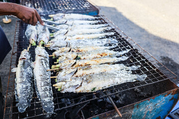 Salty snakehead fish on a charcoal grill. Snakehead fish coated with salt tablets with herbs in the...