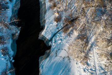 View from above on the bed of a freezing river among snow-covered winter nature