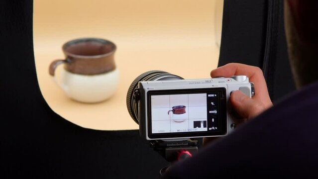 Man taking photos of coffee cup in a light box. Product photography