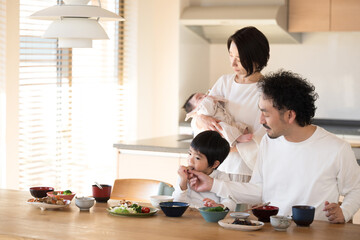 幸せな笑顔の家族 綺麗な家の食卓で食事をする家族...