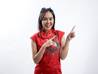 Portrait of a happy Asian woman wearing a red traditional cheongsam qipao, pointing towards a specified direction, isolated against a white background. - obrazy, fototapety, plakaty