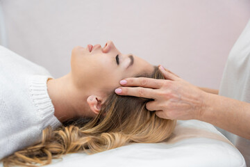 Healer performing by lightly touched set of 32 points of access bars on young woman head, stimulating positive change thoughts and emotions. Alternative medicine