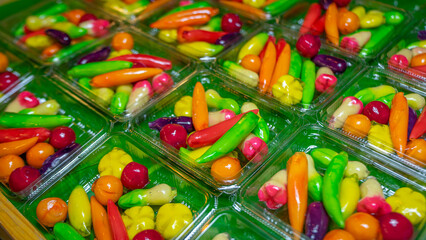 Fototapeta na wymiar Thai dessert made from beans Molded into different shapes, glossy surface, various colors, mixed together in a clear plastic box. On the green artificial grass Suitable for use as a background image