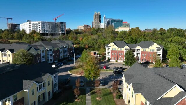 Houses in neighborhood of Raleigh, North Carolina. Aerial reveal of skyline on bright autumn day.