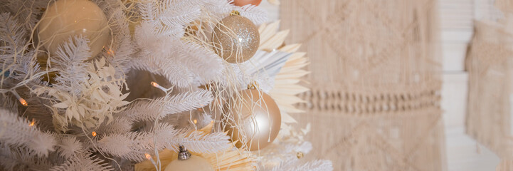 Close up of beautiful white fir branches with shiny golden, silver and white baubles or balls, shiny ornaments and garland lights, home Decoration.Festive new 2024 year. web banner.